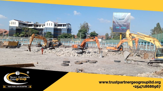 Heavy earthworks equipment in operation on a construction site in [Nairobi/Machakos/Kiambu/Nakuru], including excavators and dump trucks, performing trenching and grading with on-site safety measures